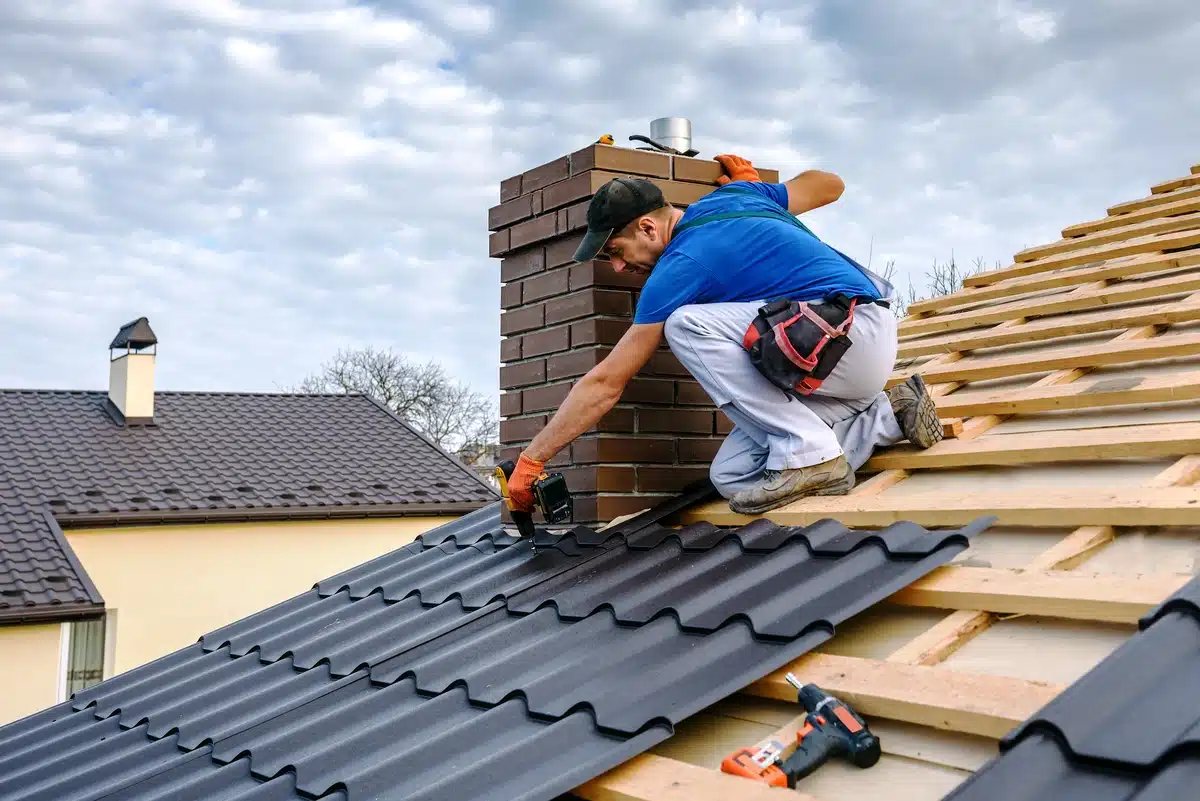 roofer drilling down metal shingles during a roof installation
