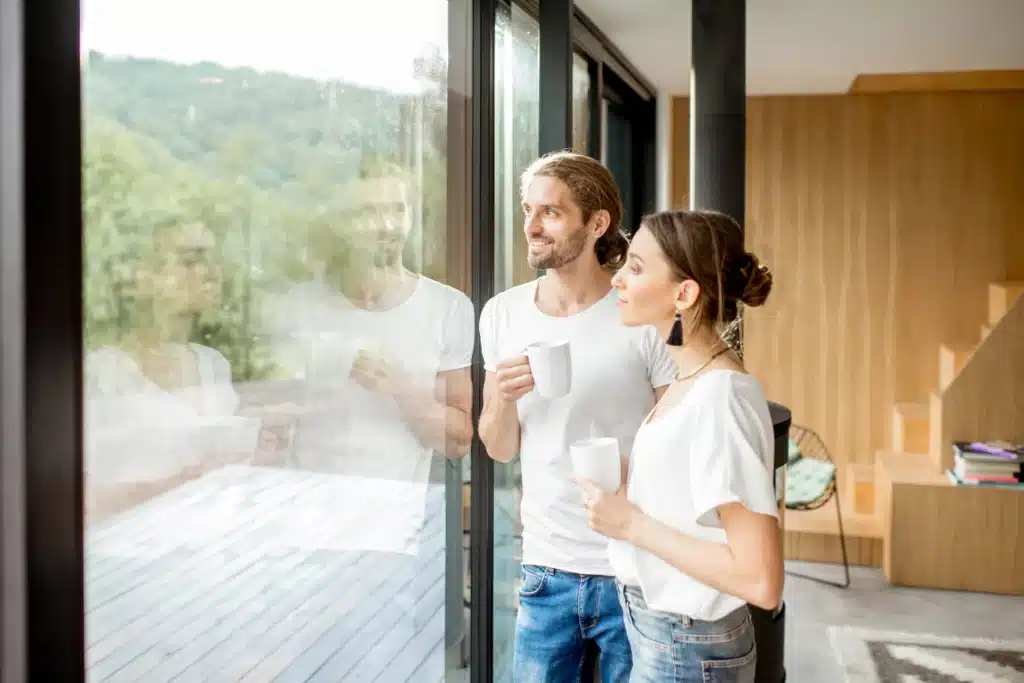 young couple in toledo home looking out of beautiful big windows after window replacement