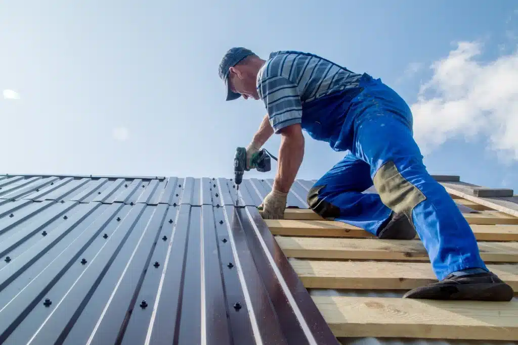 roofer on the wood structure fixing metal sheets