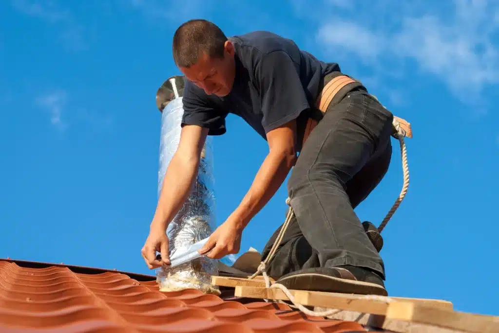 worker installing roof ventilation system on the house roof