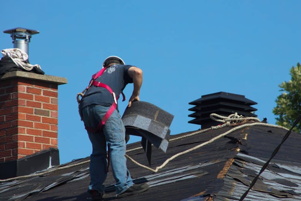 A man installing shingles on a roof, ensuring proper alignment and secure attachment for weatherproofing.