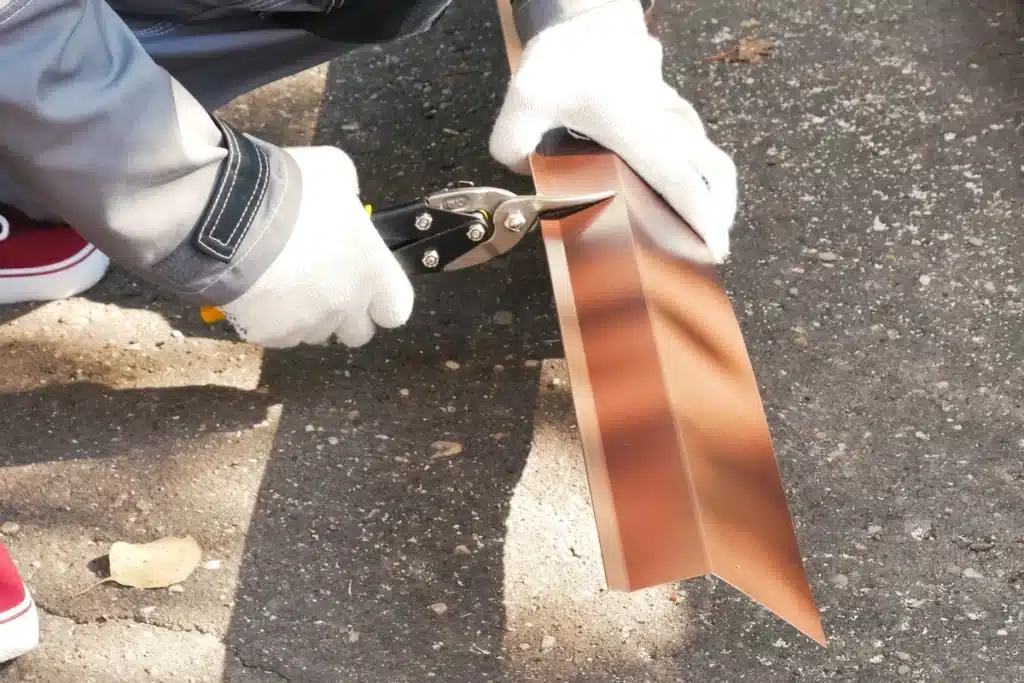 metal roof installation-roof tech wearing gloves and using hand tools to cut metal roofing materials