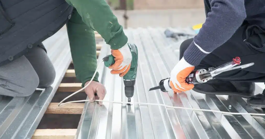 metal roof installation-two roof techs using power tools and hand tools to install metal roofing