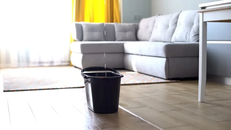 a bucket in a living room collecting water from a roof leak