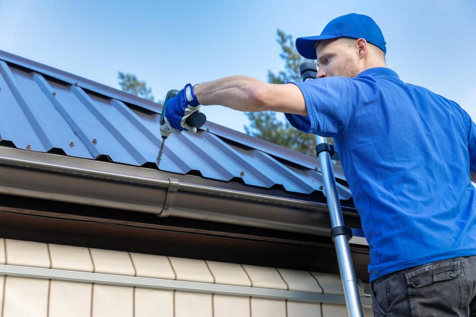 metal roofing panels-close up image of roof tech installing metal roofing on a house