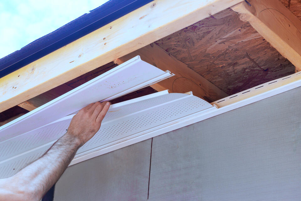 roof eaves-man installing soffits on exposed roof eaves