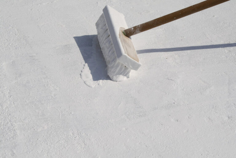 roof coating-close up image of a roof coating being applied to a flat roof with a large brush