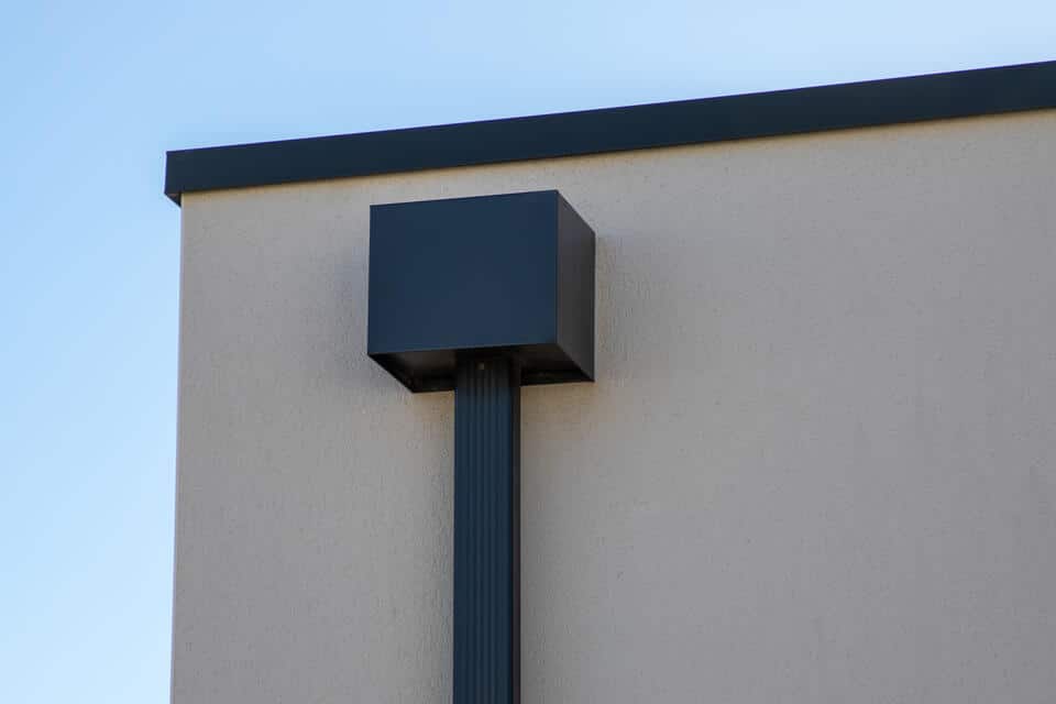 roof scupper-external view of a black roof scupper drainage system on building with a flat roof
