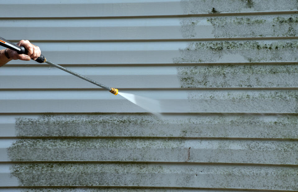 siding repair-man power washing vinyl siding to prepare it for repairs