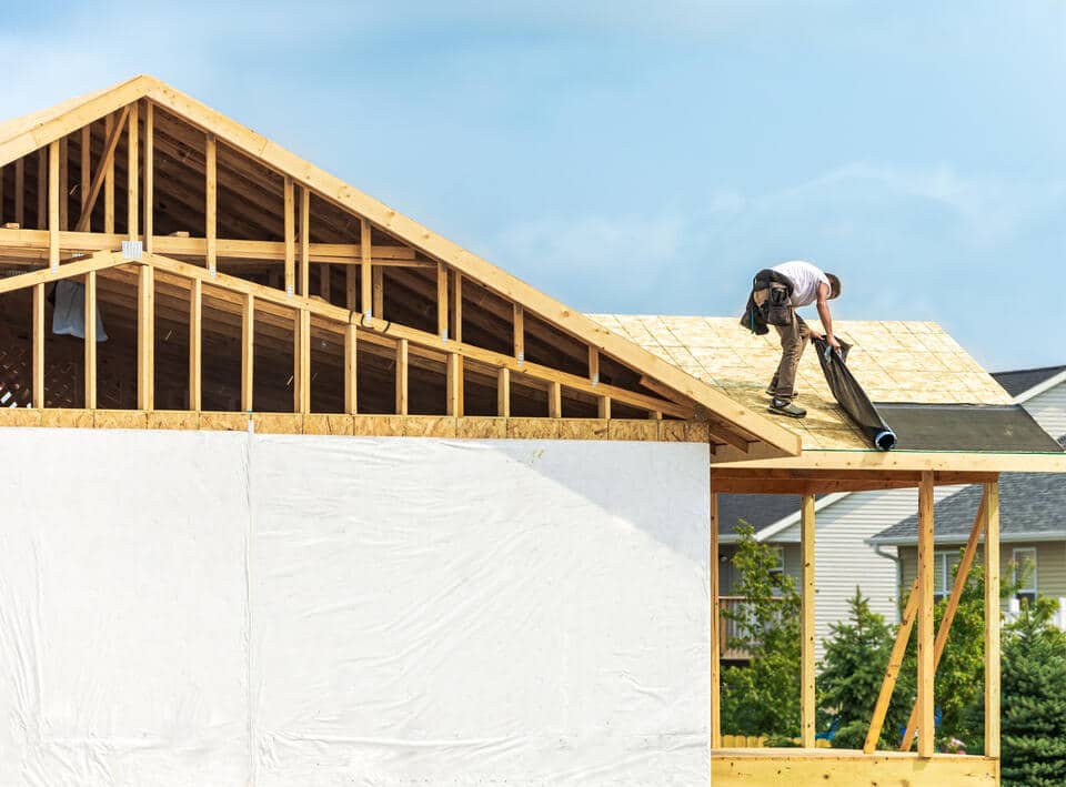 synthetic underlayment-roofer installing roof underlayment on a roof during construction