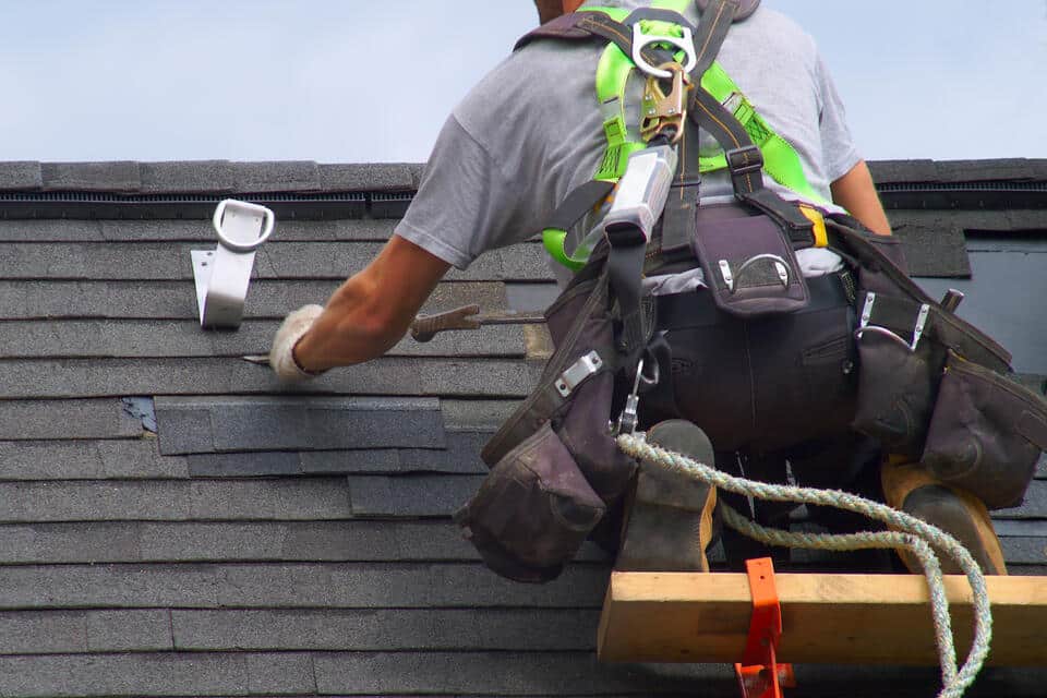 roofing tools-man on roof scaffolding using variety of tools to repair roof