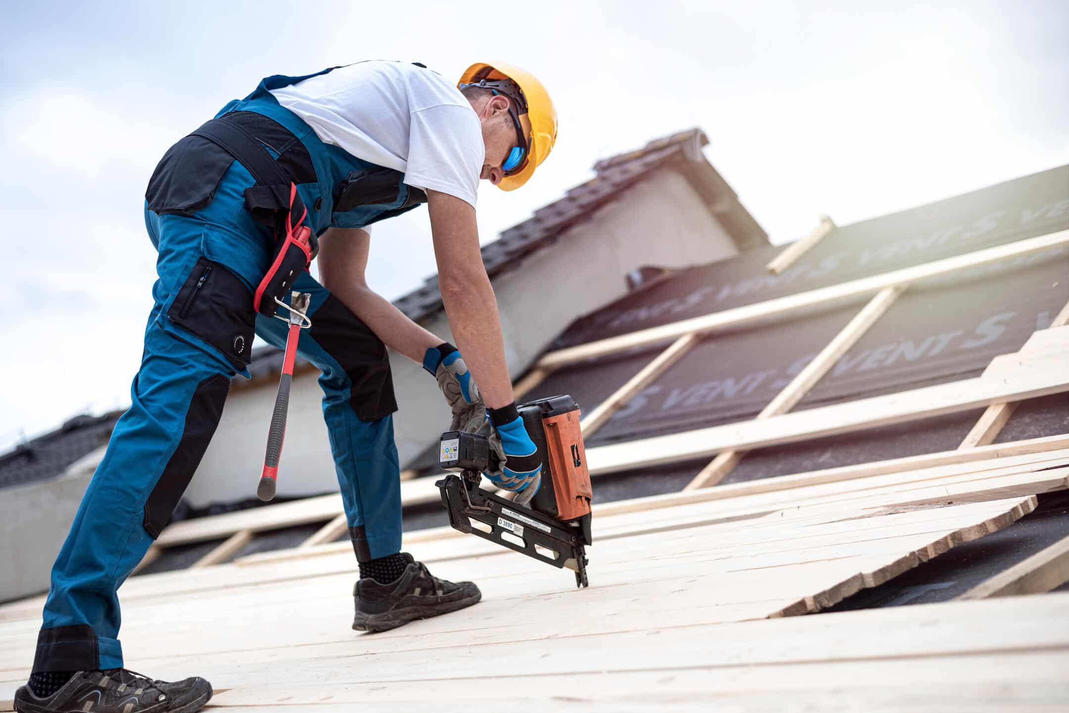 roofing tools-man standing on roof using variety of tools to install roofing