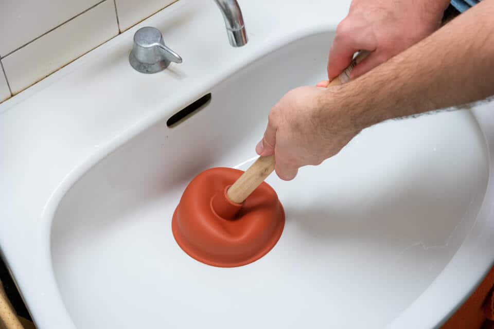 unclog bathroom sink-close up of someone plunging bathroom sink