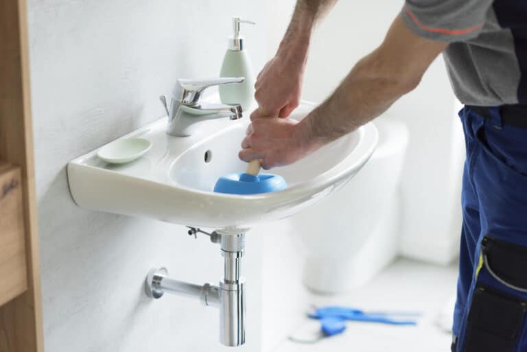 unclog bathroom sink-someone using a plunger to unclog bathroom sink