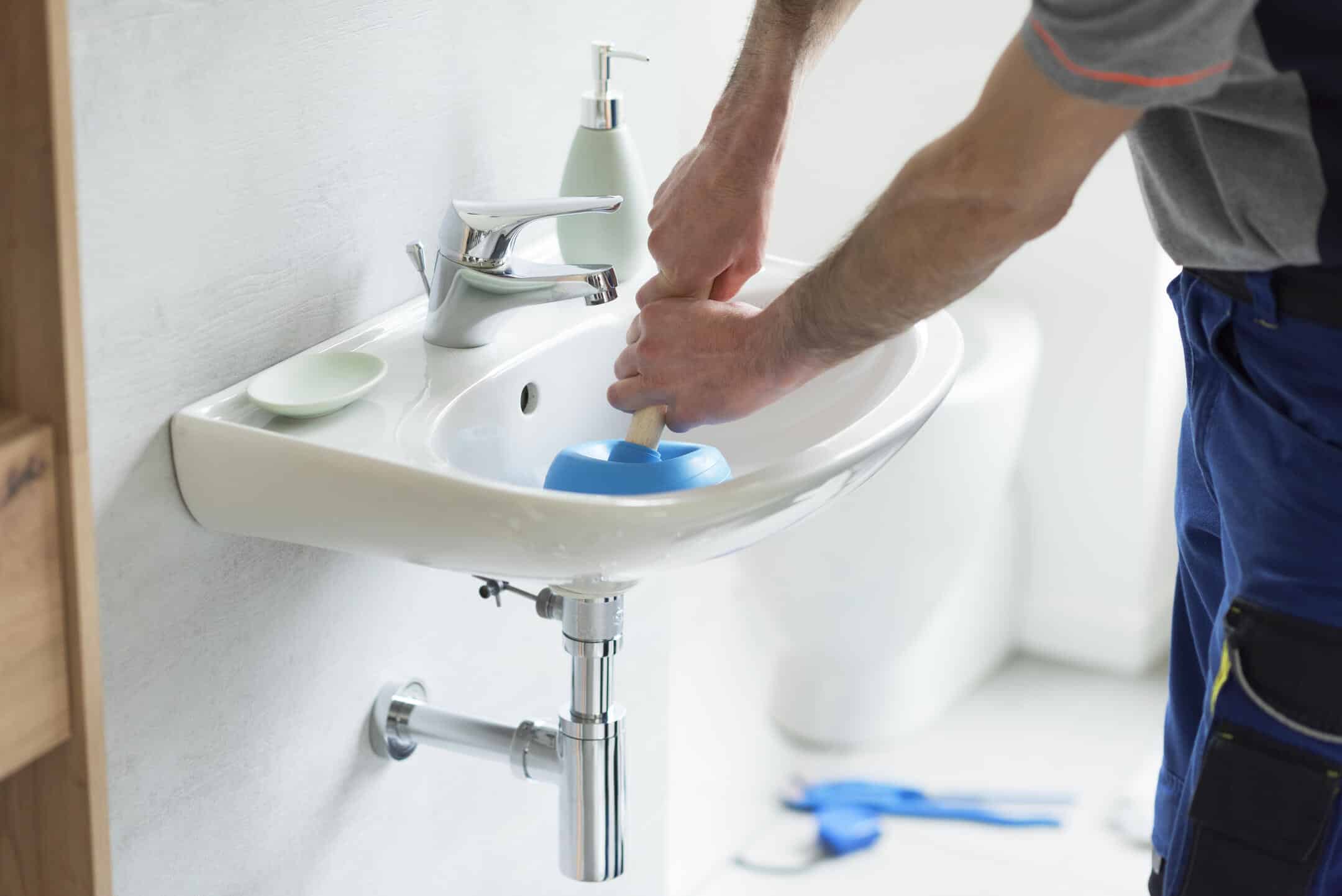 unclog bathroom sink-someone using a plunger to unclog bathroom sink