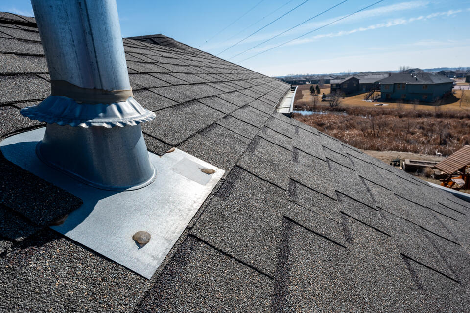 metal flashing-close up of a shingle roof with metal boot flashing